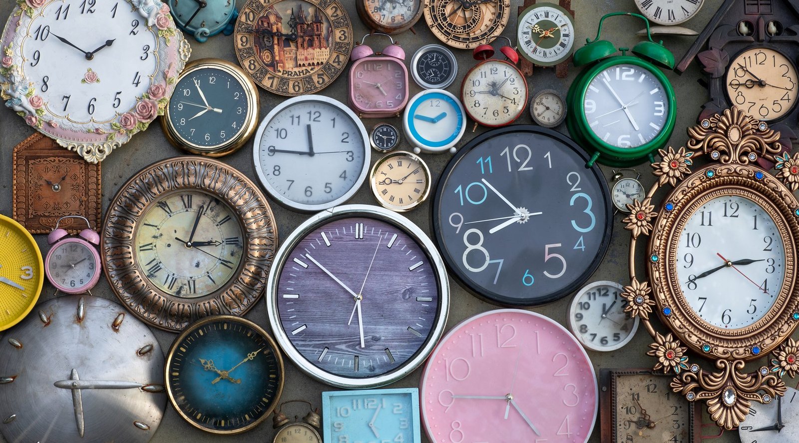A wall covered with vintage clocks, each showing a different hour