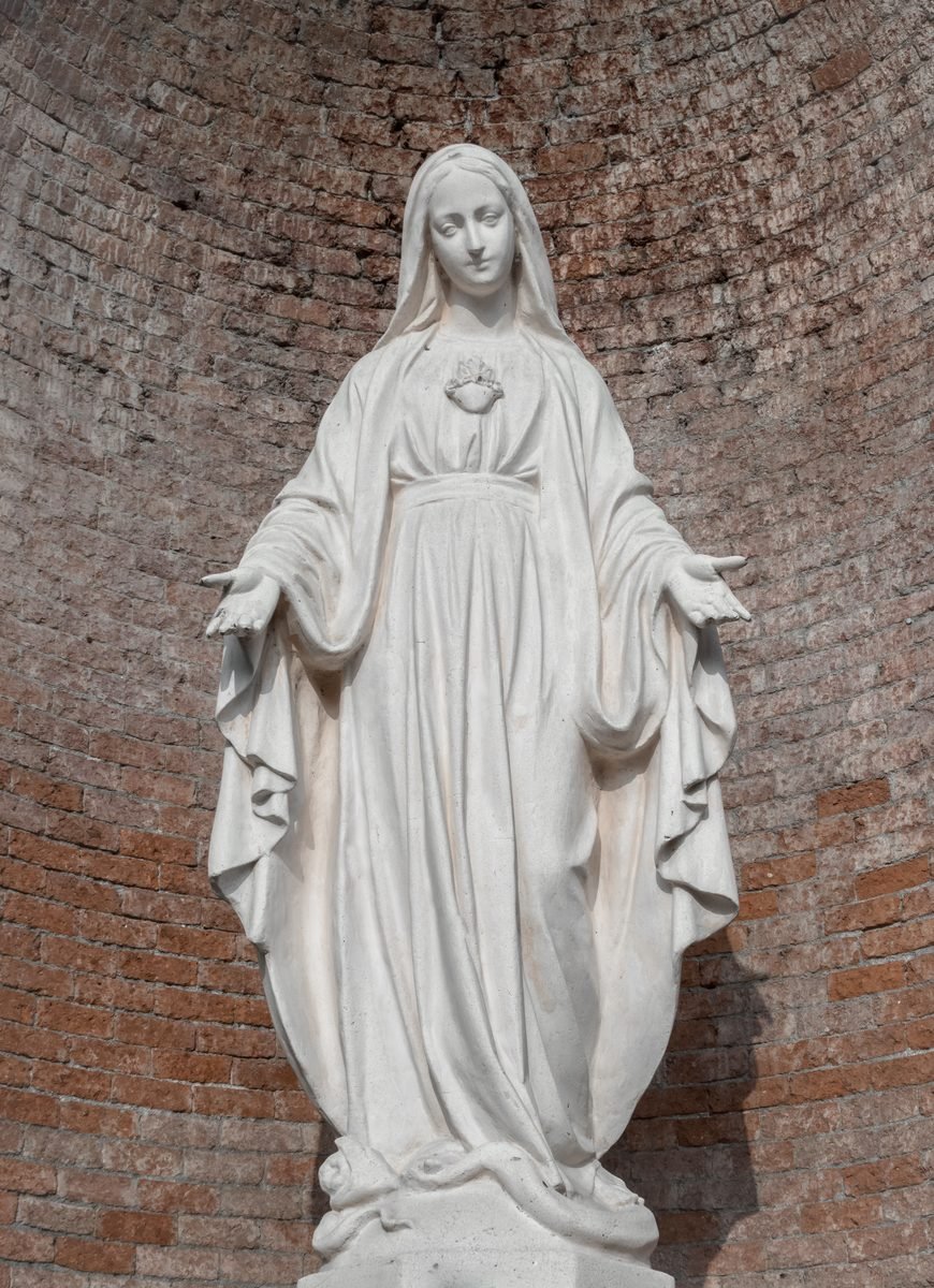 A stone statue of the Blessed Virgin with open hands